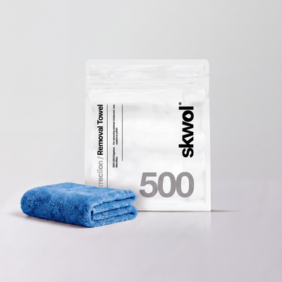 Blue folded fabric towel next to a white skwol Removal Towel bag printed with 500 GSM Edgeless Microfiber.